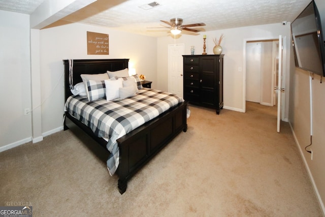 bedroom with a textured ceiling, light colored carpet, a ceiling fan, baseboards, and visible vents