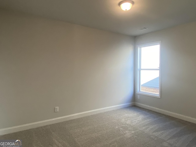 carpeted spare room featuring visible vents and baseboards