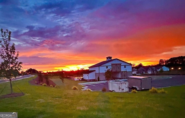 back of house at dusk featuring a lawn