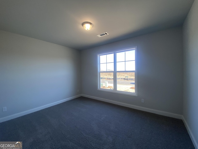 empty room featuring baseboards, visible vents, and dark colored carpet