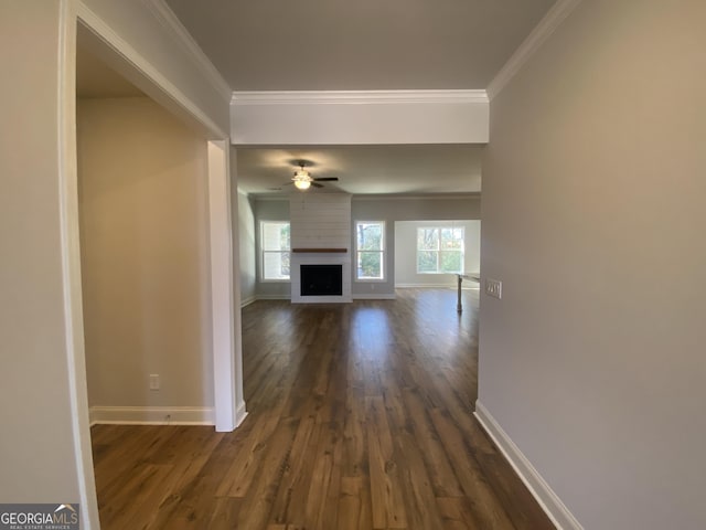 unfurnished living room with ornamental molding, a wealth of natural light, and baseboards