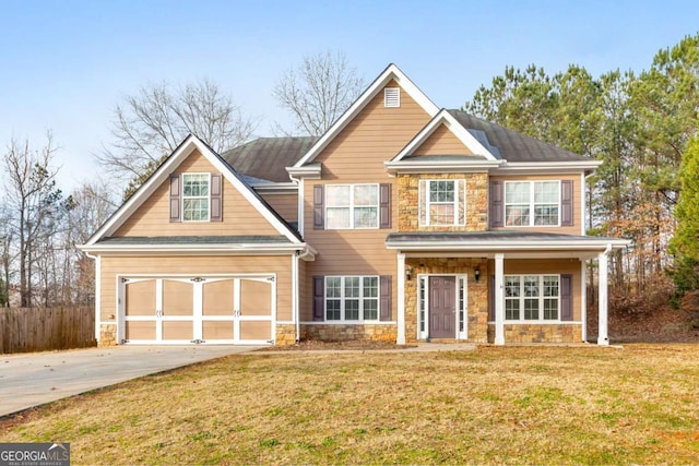 view of front of property featuring stone siding, a front lawn, fence, and driveway