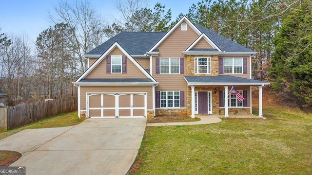 view of front of property with a garage, stone siding, a front yard, and fence