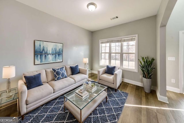 living area featuring visible vents, baseboards, and wood finished floors