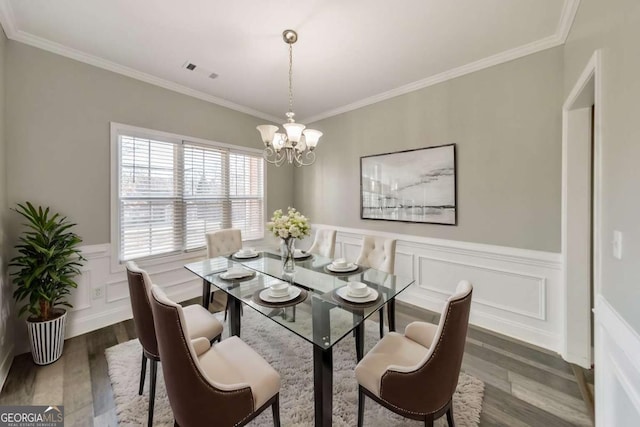 dining area featuring ornamental molding, dark wood finished floors, and a notable chandelier