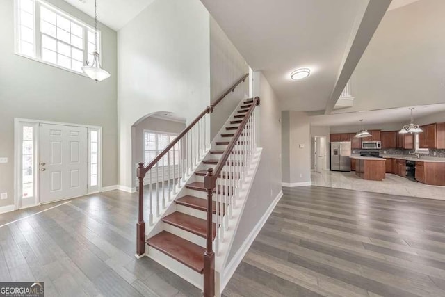 foyer entrance with light wood-style floors, plenty of natural light, stairway, and baseboards