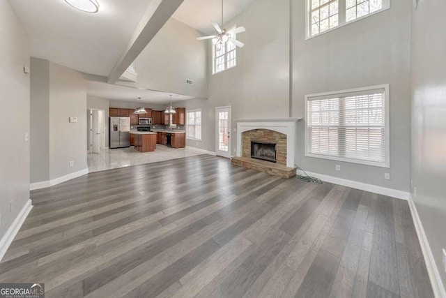 unfurnished living room with baseboards, a fireplace, light wood finished floors, and ceiling fan