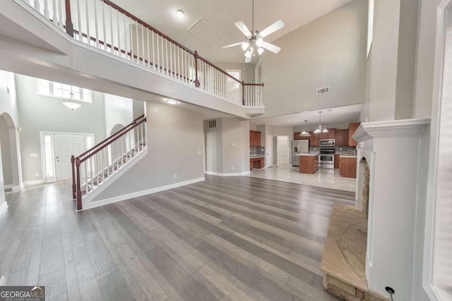 unfurnished living room featuring stairs, a ceiling fan, visible vents, and light wood-style floors