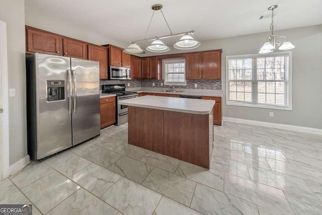 kitchen featuring a sink, marble finish floor, appliances with stainless steel finishes, light countertops, and tasteful backsplash