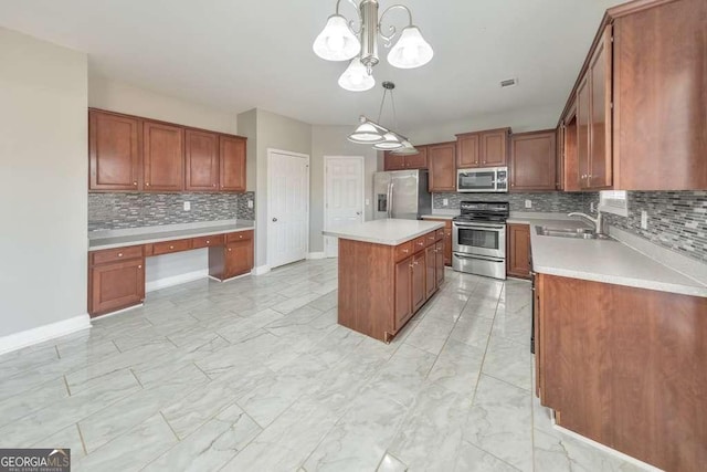 kitchen featuring marble finish floor, stainless steel appliances, light countertops, built in study area, and a kitchen island