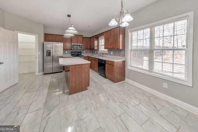 kitchen featuring a center island, stainless steel appliances, light countertops, hanging light fixtures, and decorative backsplash