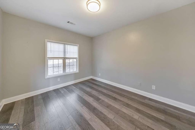 spare room featuring visible vents, dark wood finished floors, and baseboards