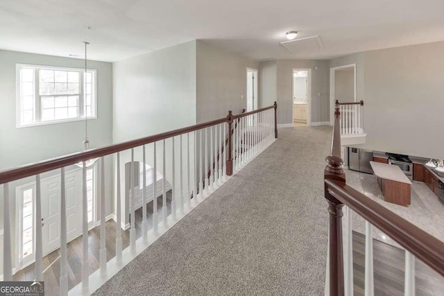 hallway with carpet flooring and an upstairs landing