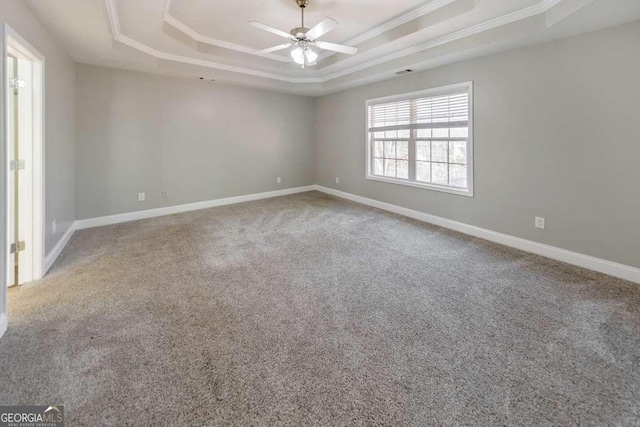 carpeted spare room with ceiling fan, baseboards, a raised ceiling, and crown molding