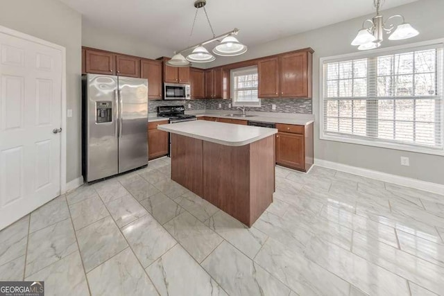 kitchen featuring backsplash, light countertops, appliances with stainless steel finishes, an inviting chandelier, and a sink