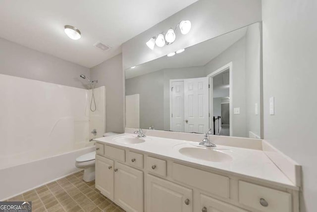 full bathroom with toilet, double vanity, a sink, and visible vents