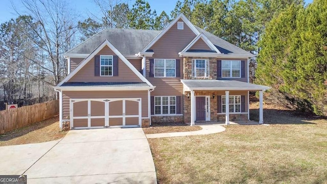 craftsman-style house featuring concrete driveway, a front yard, fence, a garage, and stone siding