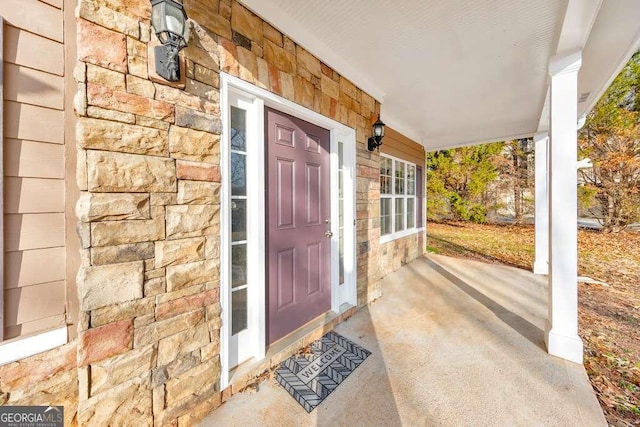 doorway to property with stone siding and a porch