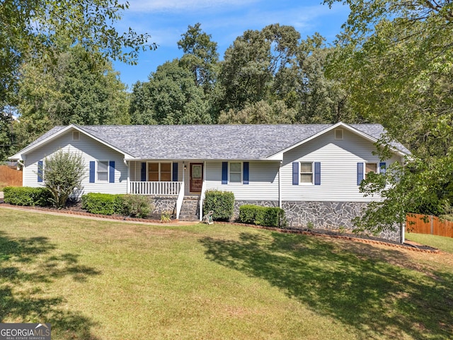 ranch-style home with covered porch, stone siding, a front yard, and fence