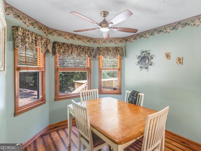 dining space with ceiling fan, a textured ceiling, baseboards, and wood finished floors