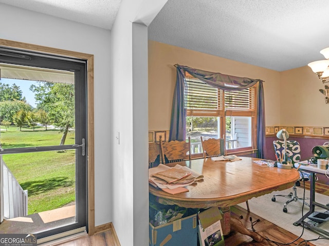 dining area featuring a textured ceiling, a chandelier, wood finished floors, and baseboards