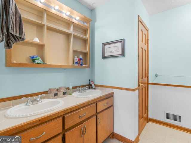 bathroom featuring double vanity, wainscoting, a sink, and visible vents