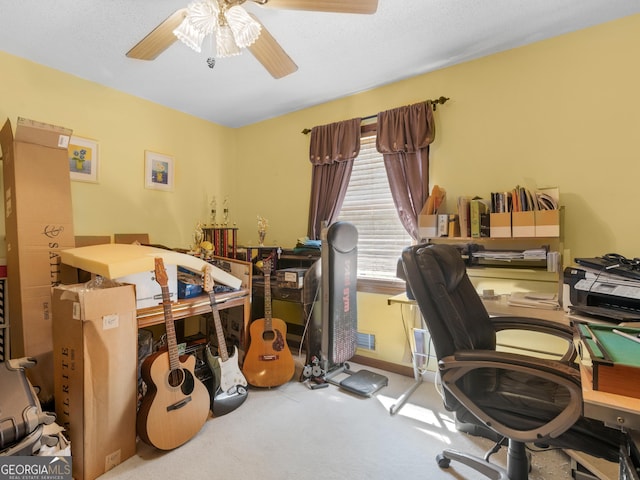 carpeted office space with a ceiling fan and baseboards