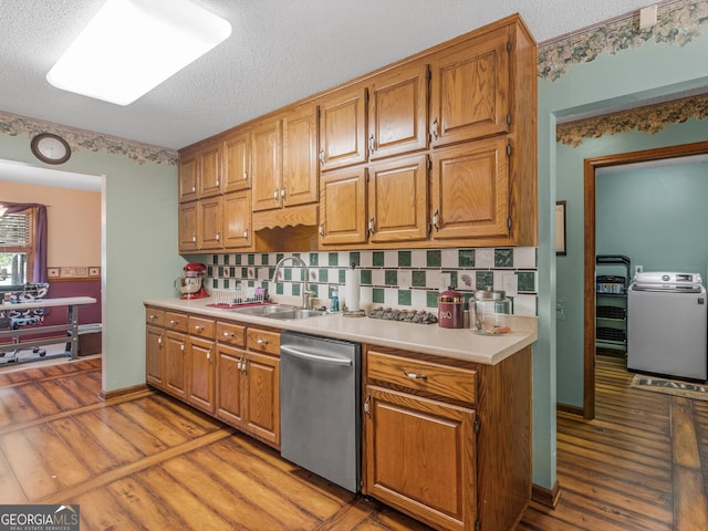 kitchen featuring dishwasher, washer / clothes dryer, light countertops, light wood-type flooring, and a sink