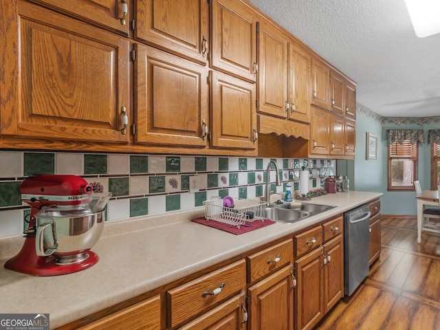 kitchen featuring light countertops, brown cabinets, a sink, and stainless steel dishwasher