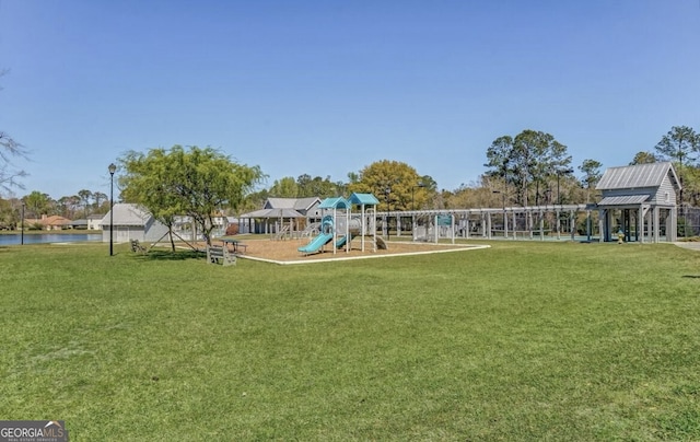 exterior space featuring playground community, a lawn, and a water view