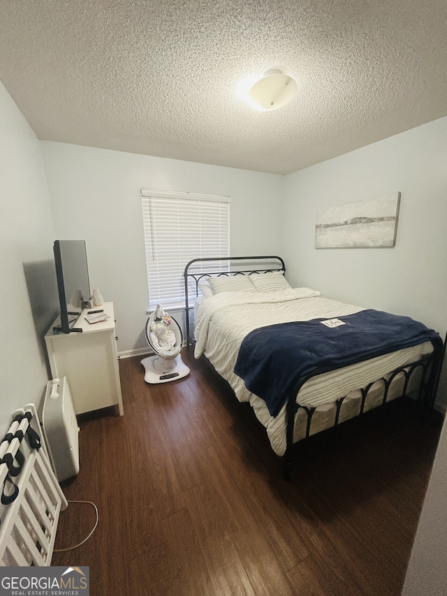 bedroom featuring a textured ceiling, baseboards, and wood finished floors