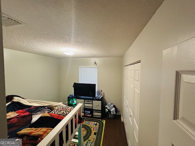 bedroom with a closet, visible vents, a textured ceiling, and wood finished floors