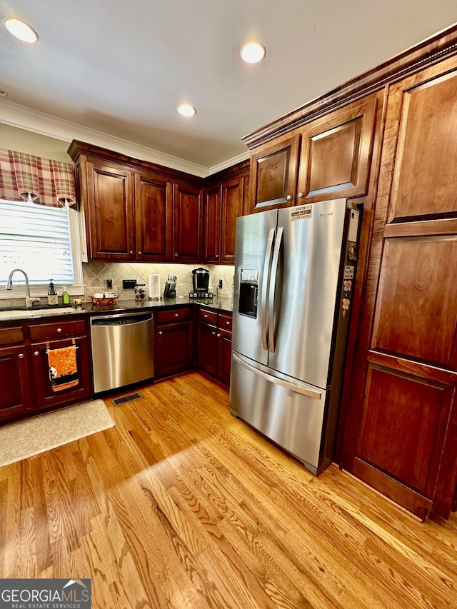 3585 Shepherds Ln, Loganville, GA 30052 - kitchen with stainless steel appliances, a sink, light wood-style floors, tasteful backsplash, and crown molding