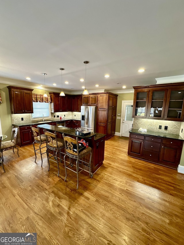 3585 Shepherds Ln, Loganville, GA 30052 - kitchen featuring a breakfast bar, a center island, tasteful backsplash, light wood-type flooring, and stainless steel fridge with ice dispenser