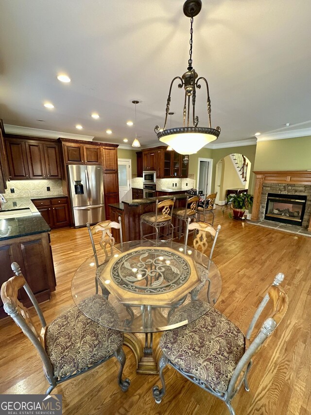 3585 Shepherds Ln, Loganville, GA 30052 - dining space with a glass covered fireplace, crown molding, light wood finished floors, and recessed lighting