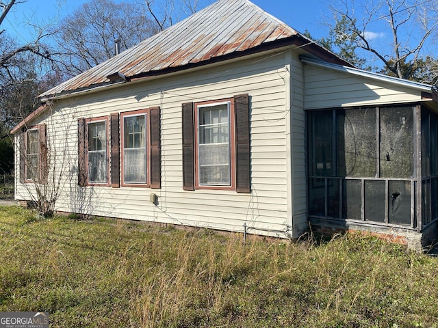 view of side of property with a sunroom, metal roof, and a lawn