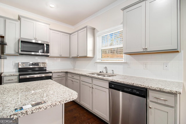 kitchen with appliances with stainless steel finishes, gray cabinets, a sink, and ornamental molding