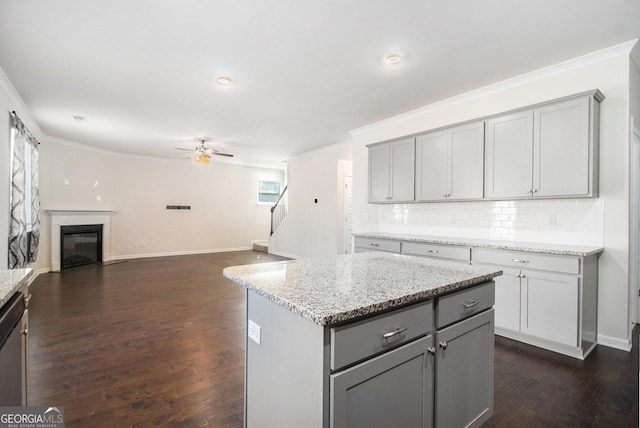 kitchen with a glass covered fireplace, gray cabinets, crown molding, and backsplash