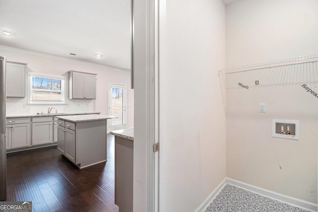 clothes washing area with dark wood finished floors, crown molding, hookup for a washing machine, cabinet space, and baseboards