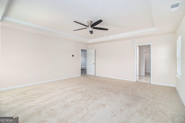 unfurnished bedroom featuring carpet flooring, a ceiling fan, visible vents, baseboards, and a raised ceiling