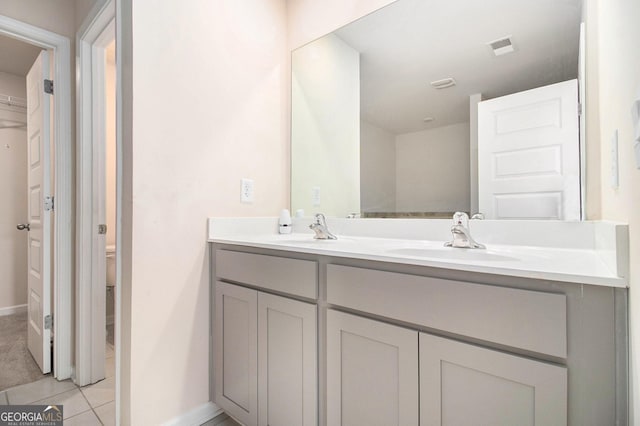 bathroom with double vanity, visible vents, toilet, and a sink