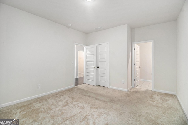 unfurnished bedroom with carpet floors, ensuite bath, and baseboards