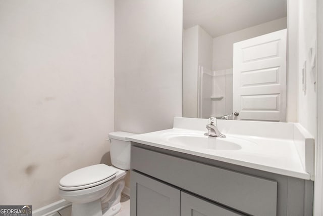 bathroom with toilet, baseboards, and vanity