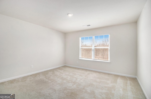 empty room featuring visible vents, baseboards, and light colored carpet