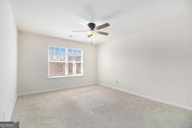 carpeted spare room with baseboards, visible vents, and a ceiling fan