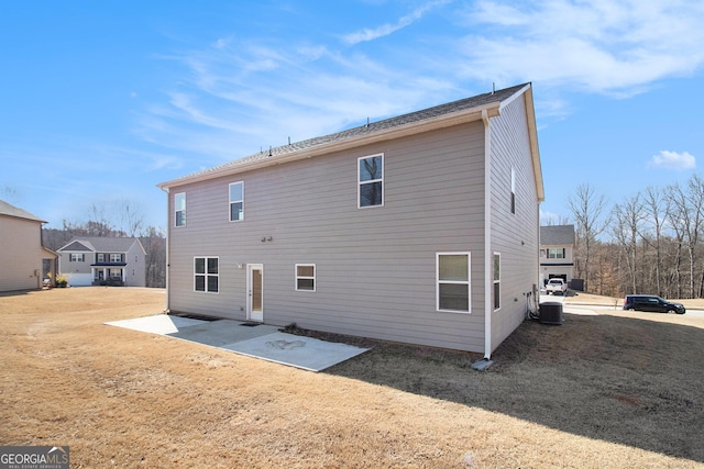 rear view of property with a patio area, central AC unit, and a yard