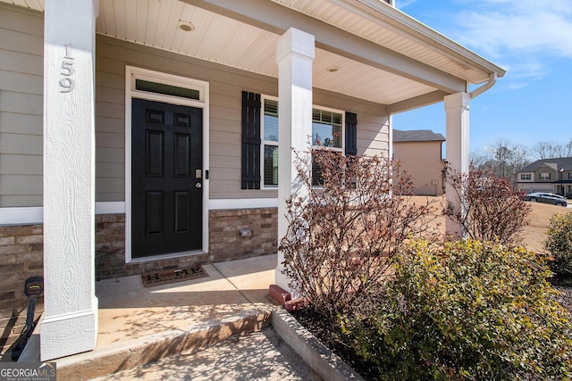 entrance to property featuring stone siding and covered porch