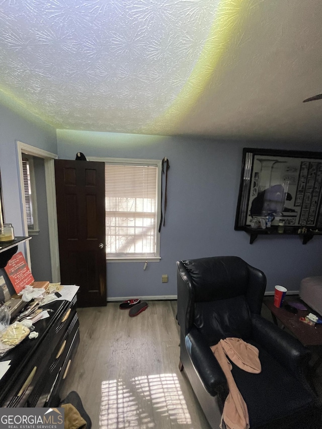 bedroom with a textured ceiling, baseboards, and wood finished floors