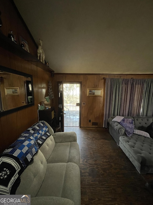 living room featuring lofted ceiling and wood walls