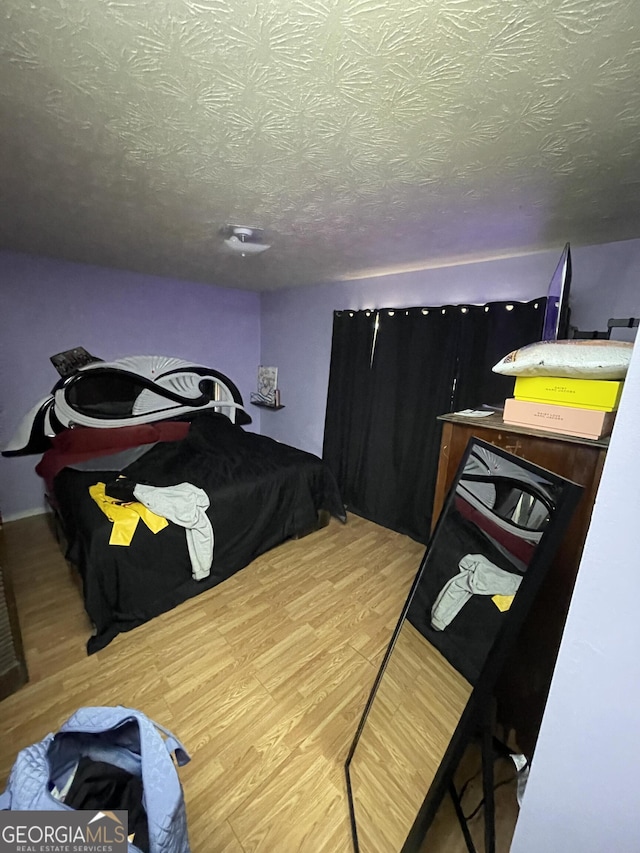 bedroom with a textured ceiling and wood finished floors